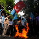 Ethnic Uighur demonstrators, waving Turkish and blue East Turkestan flags, set fire to a Chinese flag during a protest against China near the Chinese Consulate in Istanbul July 21, 2011. China on Wednesday raised the death toll to 18 from a clash at a police station in the restive far western region of Xinjiang, saying that 14 "rioters" died along with two policemen and two hostages in the worst violence there in a year. Government officials previously said at least four people were killed in what they described as a terrorist attack. But the Germany-based exile group World Uyghur Congress said it was an attack on unarmed protesters.
